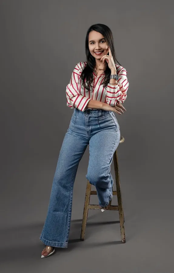 Aylla sentada em um banco alto, sorrindo.